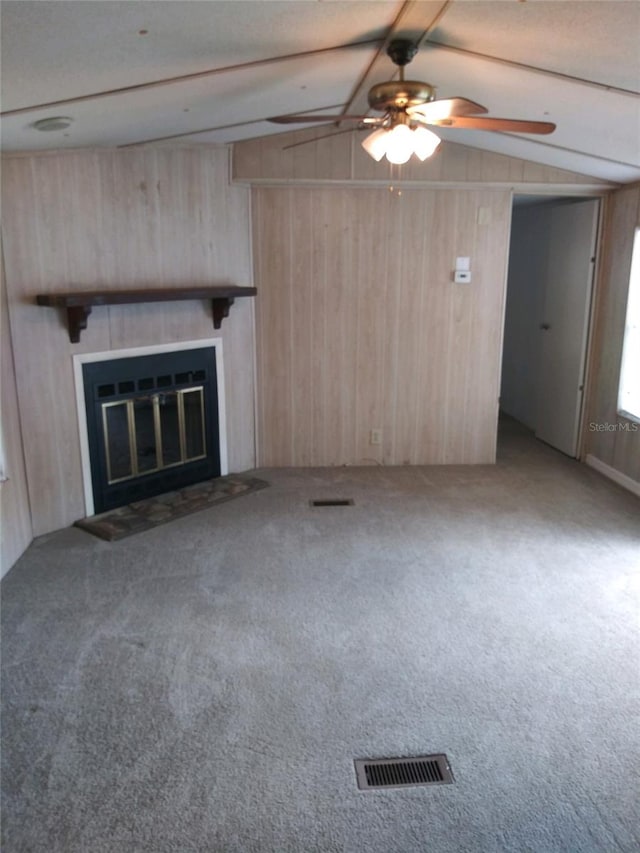 unfurnished living room featuring ceiling fan, carpet floors, and wooden walls