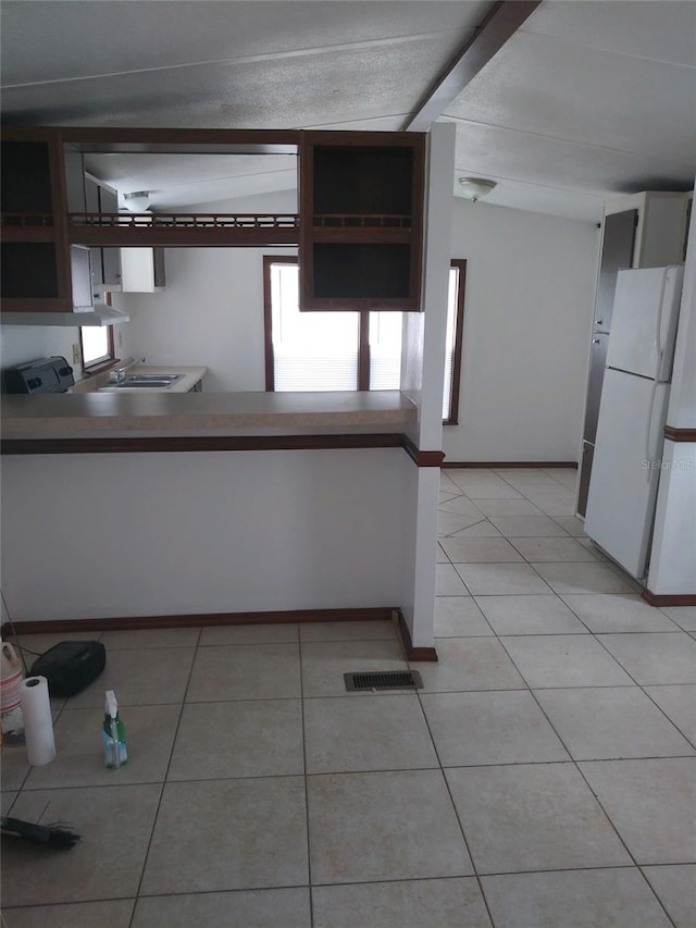 kitchen with visible vents, a sink, light tile patterned floors, freestanding refrigerator, and baseboards