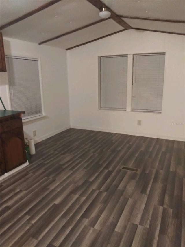 unfurnished living room featuring wood finished floors, vaulted ceiling with beams, and baseboards