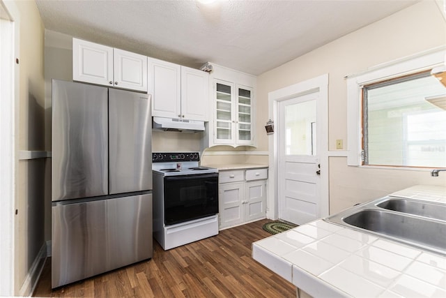 kitchen featuring tile countertops, a textured ceiling, stainless steel fridge, white cabinetry, and white electric range