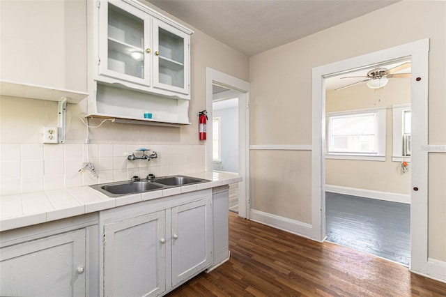 kitchen with tile countertops, dark wood-type flooring, sink, white cabinets, and a textured ceiling