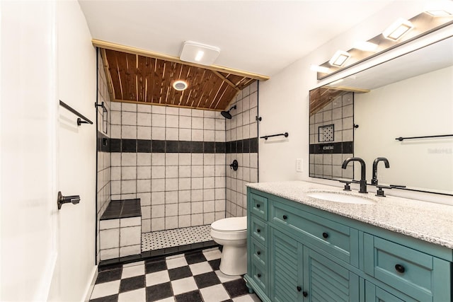 bathroom with vanity, toilet, tile walls, and a tile shower