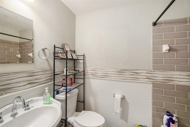 bathroom featuring sink, tile walls, and toilet