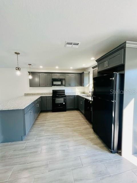 kitchen featuring kitchen peninsula, decorative light fixtures, black appliances, and light stone counters