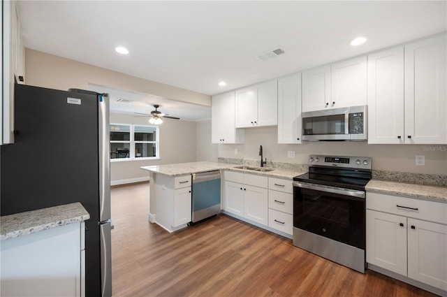 kitchen featuring hardwood / wood-style floors, stainless steel appliances, white cabinets, sink, and kitchen peninsula