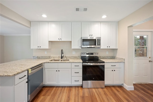 kitchen with light hardwood / wood-style floors, sink, kitchen peninsula, appliances with stainless steel finishes, and white cabinetry