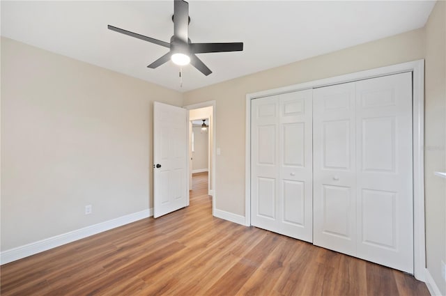 unfurnished bedroom featuring ceiling fan, a closet, and wood-type flooring