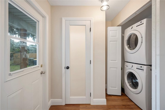 laundry room with stacked washing maching and dryer and hardwood / wood-style flooring