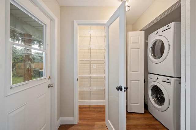 washroom with hardwood / wood-style flooring and stacked washer / dryer