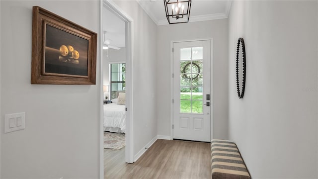 entryway with ceiling fan with notable chandelier, light wood-type flooring, and ornamental molding