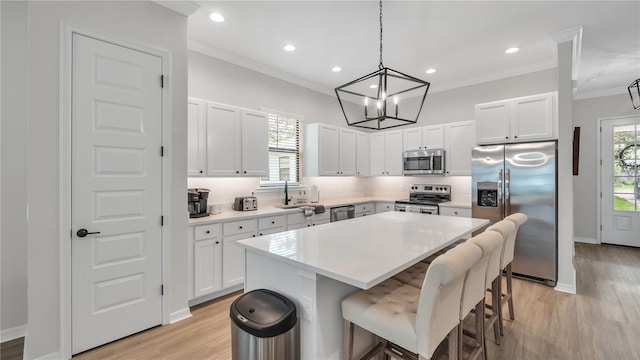 kitchen with appliances with stainless steel finishes, hanging light fixtures, a center island, and white cabinets