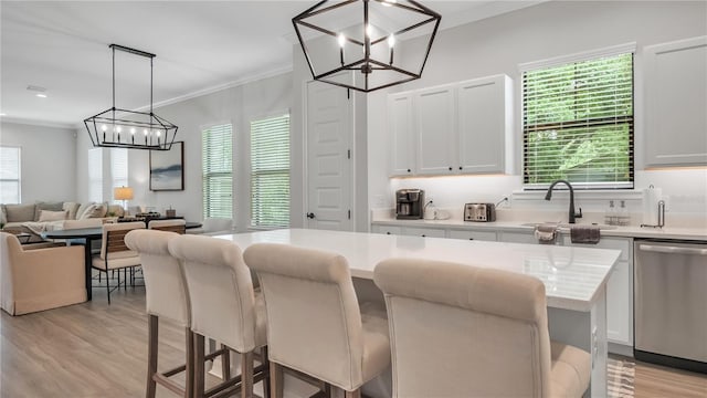 kitchen featuring hanging light fixtures, stainless steel dishwasher, white cabinetry, a kitchen breakfast bar, and light hardwood / wood-style floors