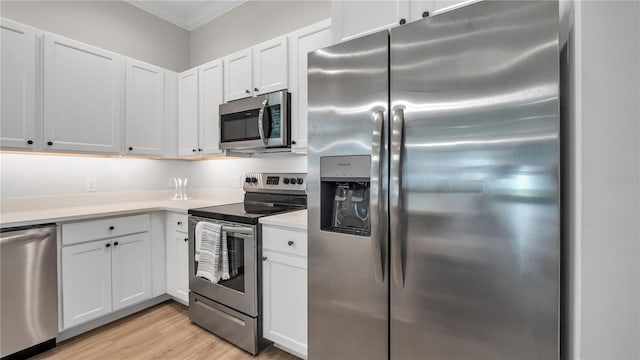 kitchen featuring ornamental molding, light wood-type flooring, stainless steel appliances, and white cabinets