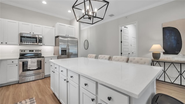 kitchen featuring stainless steel appliances, hanging light fixtures, a kitchen island, and white cabinetry