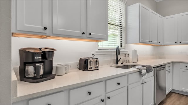 kitchen with light stone countertops, white cabinets, sink, light hardwood / wood-style flooring, and dishwasher