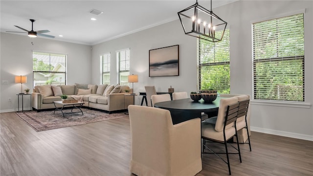 dining room featuring ceiling fan with notable chandelier, ornamental molding, and hardwood / wood-style flooring