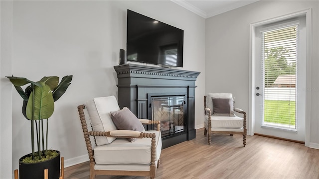 living area with light hardwood / wood-style floors and crown molding