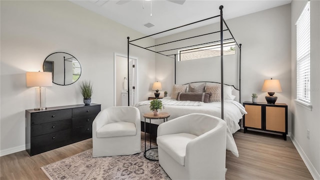 bedroom featuring ceiling fan, light hardwood / wood-style flooring, and connected bathroom