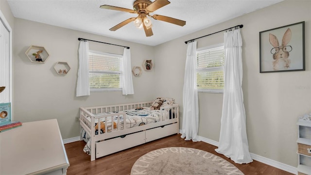 bedroom featuring multiple windows, ceiling fan, and dark hardwood / wood-style flooring