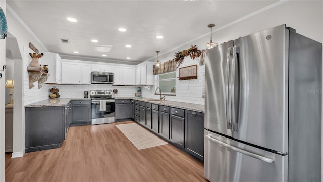 kitchen featuring white cabinetry, sink, stainless steel appliances, light hardwood / wood-style floors, and decorative light fixtures