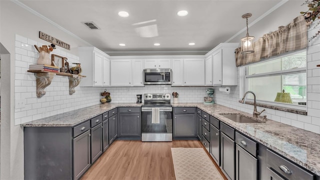 kitchen featuring white cabinets, sink, light hardwood / wood-style flooring, appliances with stainless steel finishes, and decorative light fixtures