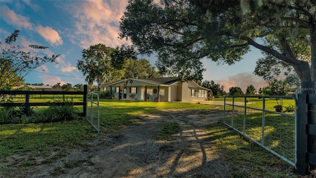 gate at dusk featuring covered porch and a yard