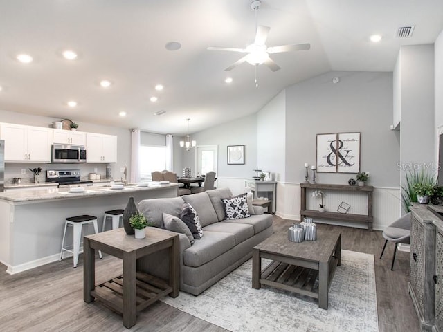 living room with ceiling fan with notable chandelier, lofted ceiling, sink, and light hardwood / wood-style flooring