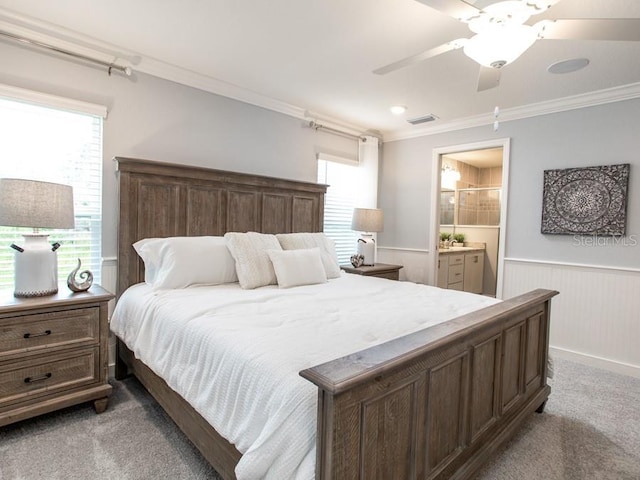 carpeted bedroom with crown molding, ensuite bathroom, and ceiling fan