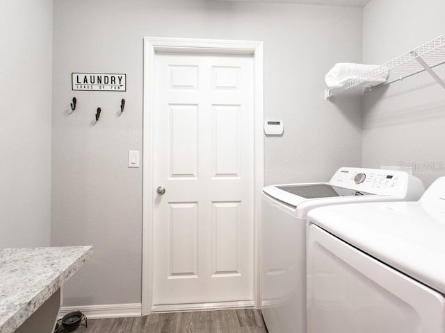 laundry room featuring washing machine and clothes dryer and hardwood / wood-style floors