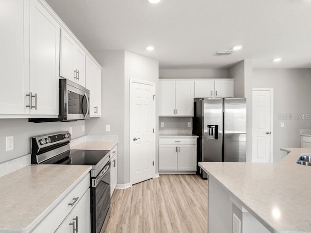 kitchen featuring white cabinets, stainless steel appliances, and light hardwood / wood-style flooring