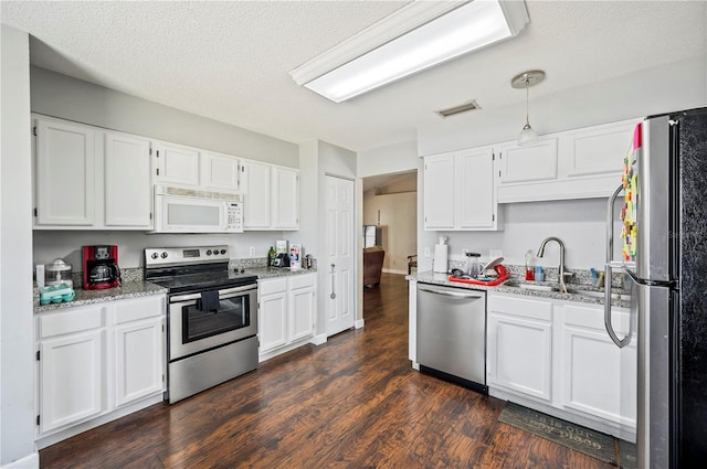 941 Devonshire Way, Lake Wales, FL 33853 - kitchen with stainless steel appliances, a sink, white cabinetry, dark wood-type flooring, and a textured ceiling