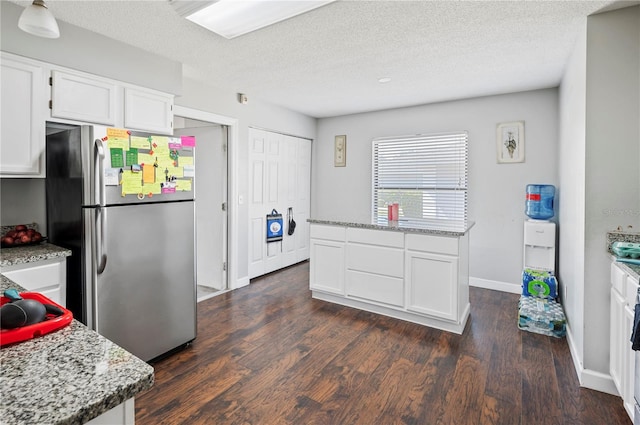 kitchen featuring stainless steel fridge, dark hardwood / wood-style flooring, white cabinetry, light stone countertops, and a textured ceiling