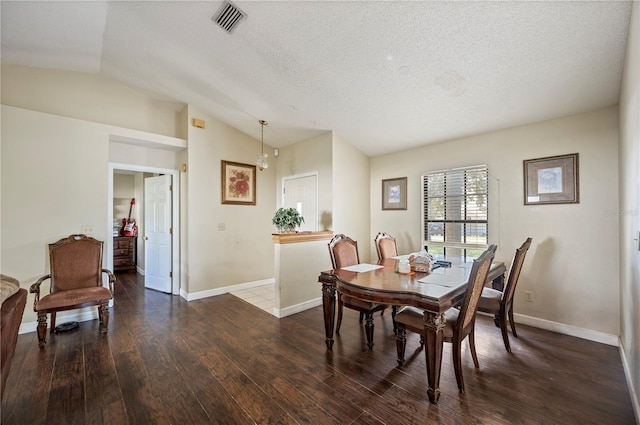 dining area featuring a textured ceiling, vaulted ceiling, and dark hardwood / wood-style floors