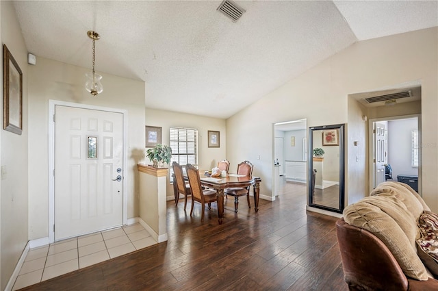 foyer with a textured ceiling, wood-type flooring, and vaulted ceiling