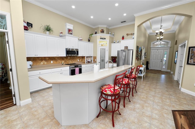 kitchen with stainless steel appliances, a large island, arched walkways, recessed lighting, and backsplash