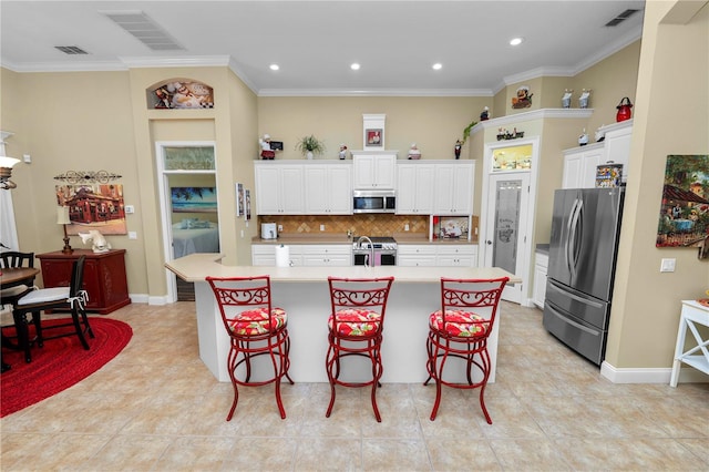 kitchen featuring backsplash, an island with sink, a kitchen bar, crown molding, and stainless steel appliances