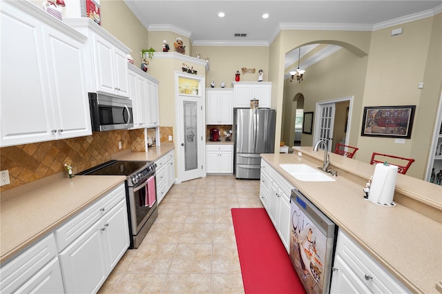 kitchen with crown molding, white cabinets, stainless steel appliances, and sink