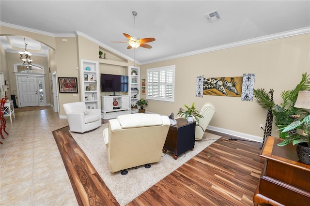 living room featuring ornamental molding, vaulted ceiling, tile patterned flooring, and ceiling fan with notable chandelier