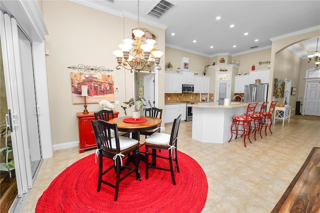 dining room with sink, light tile patterned floors, ornamental molding, and an inviting chandelier