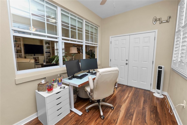 office featuring baseboards, a ceiling fan, heating unit, and wood finished floors