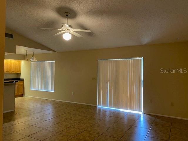 tiled empty room with ceiling fan, a textured ceiling, and lofted ceiling