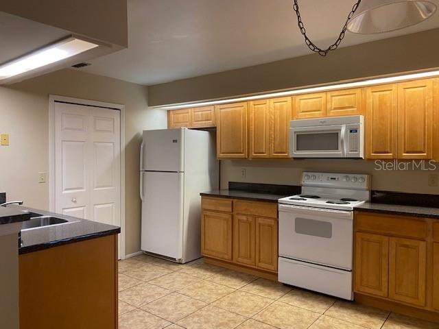 kitchen with white appliances, light tile patterned floors, and sink