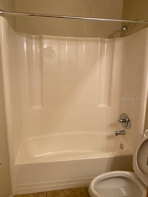 bathroom with tile patterned floors, toilet, and  shower combination