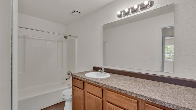 bathroom featuring shower / bath combination, visible vents, a textured wall, toilet, and vanity