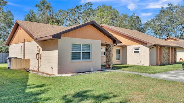 view of front of home with roof with shingles, fence, and a front lawn