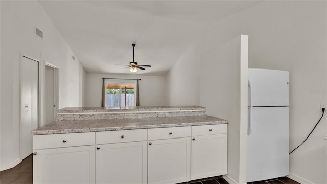 kitchen with visible vents, dark wood-style flooring, freestanding refrigerator, a peninsula, and white cabinetry