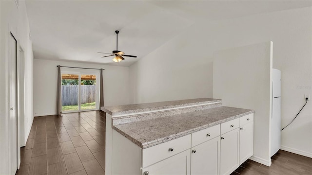 kitchen with white cabinets, dark wood finished floors, ceiling fan, a peninsula, and light stone countertops