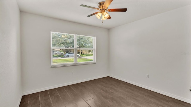 spare room featuring dark wood-type flooring, a ceiling fan, and baseboards