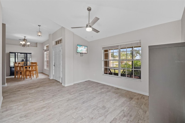 unfurnished living room with lofted ceiling, light hardwood / wood-style flooring, and ceiling fan with notable chandelier