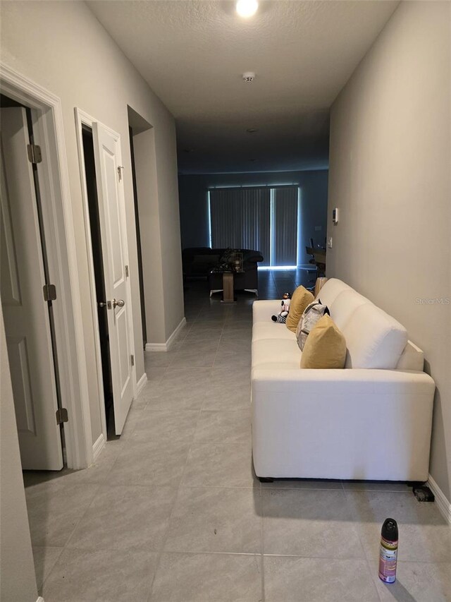 hall featuring a textured ceiling and baseboards